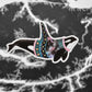 Orca sticker, wearing a sweater with planets and galaxy artwork.