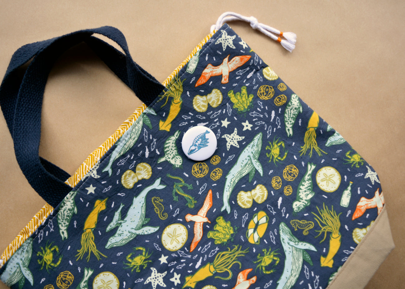 Pin back button with an imaginative skeleton whale on a cloth bag.