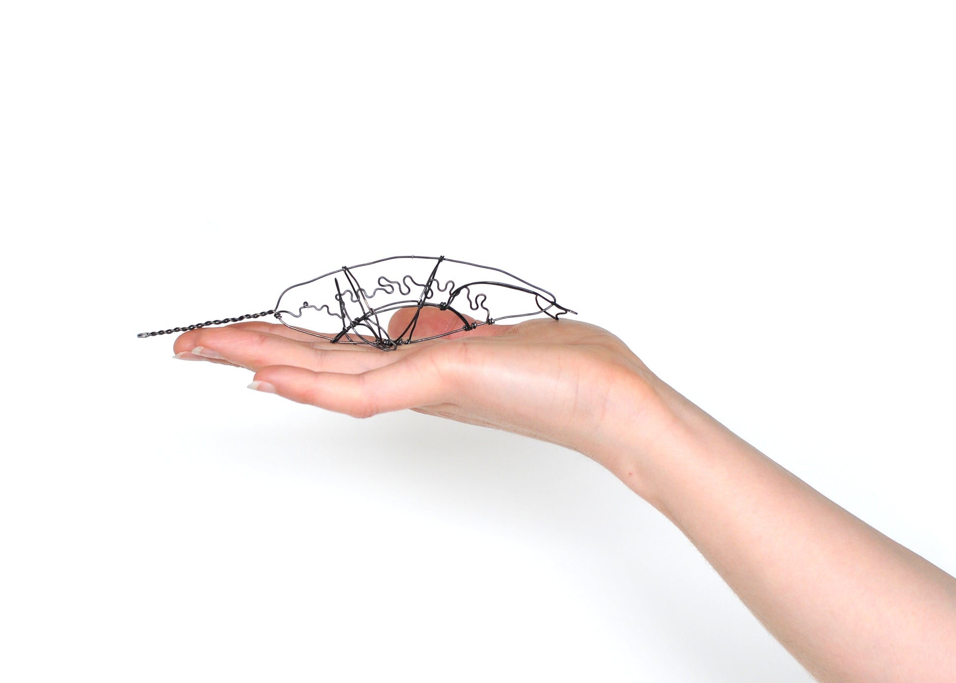 Photo of a 3D wire narwhal whale sculpture. Held in a hand.
