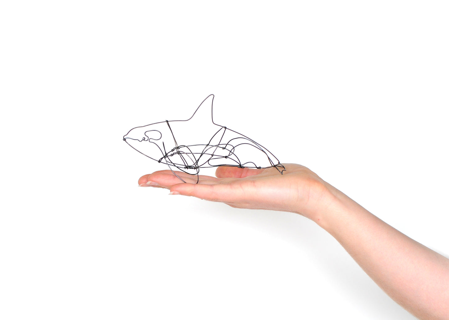 Photo of a 3D wire orca whale sculpture held in a hand.