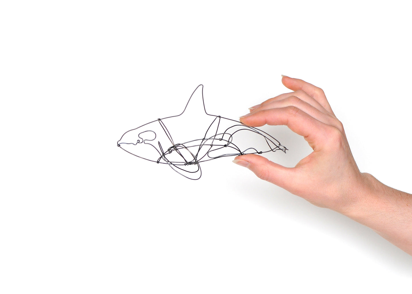 Photo of a 3D wire orca whale sculpture held in a hand.