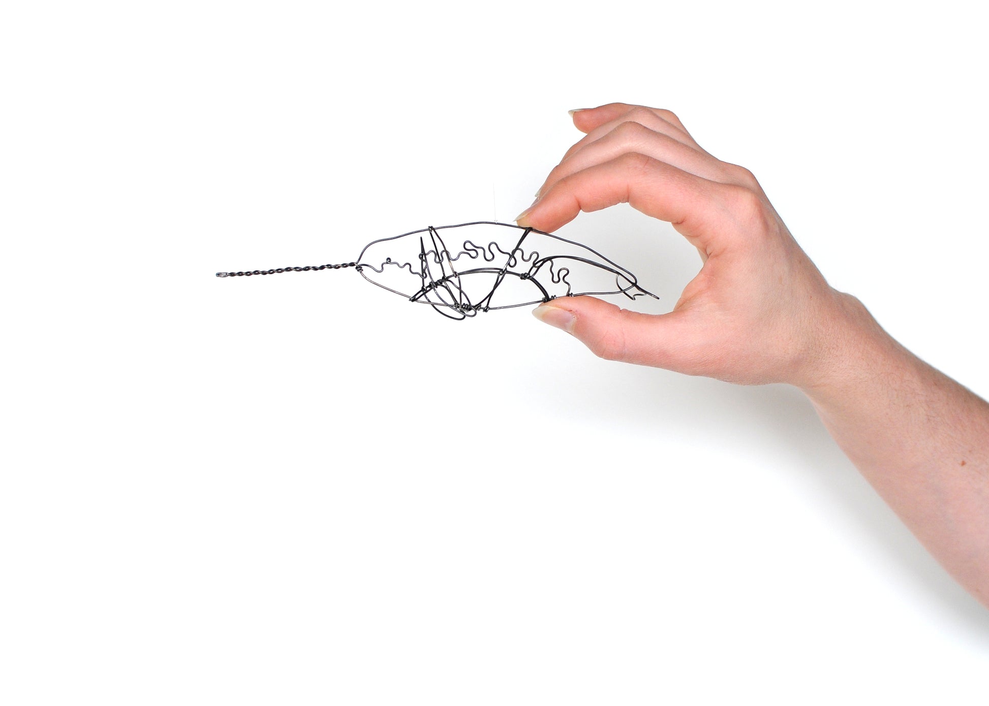 Photo of a 3D wire narwhal whale sculpture held in a hand.