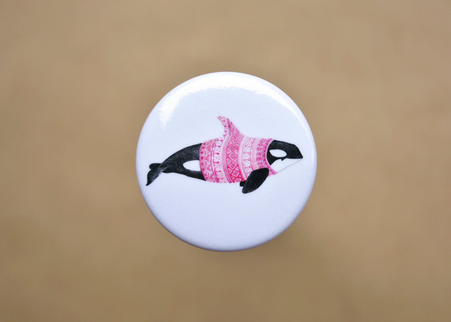 Ink drawing of a humpback whale wearing a pink sweater on a pin-backed button.